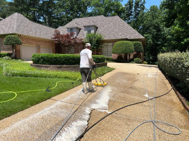 professional pressure washing concrete driveway of brick home